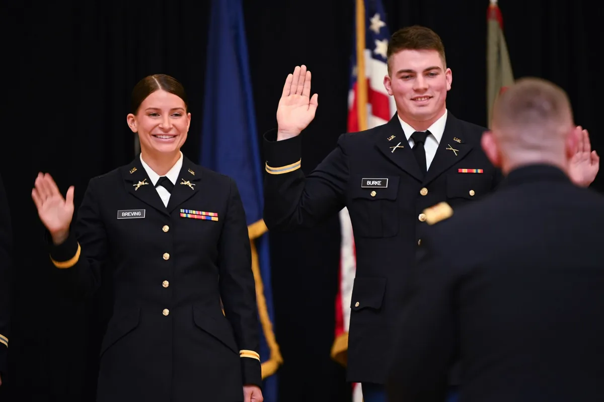Two newly commissioned Army second lieutenants raise their right hands and take the oath of office at an ROTC commissioning ceremony