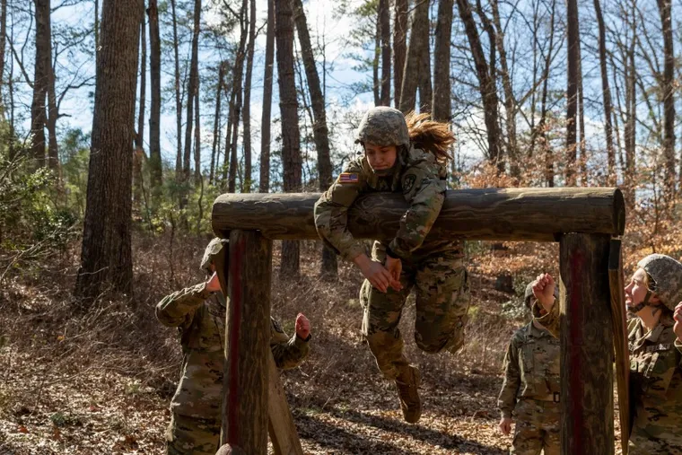 Army ROTC cadet vaulting a log obstacle on a Ranger Challenge course in the woods.