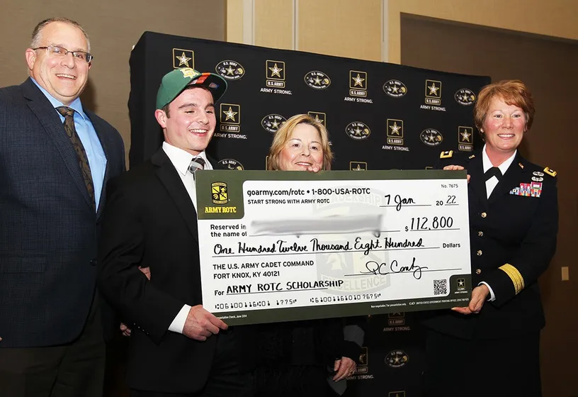 A student and his parents receiving an oversized presentation check for a four-year Army ROTC scholarship