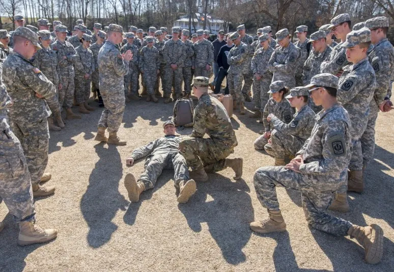 An instructor demonstrates casualty evaluation to a circle of Army ROTC cadets during first aid training at Clemson