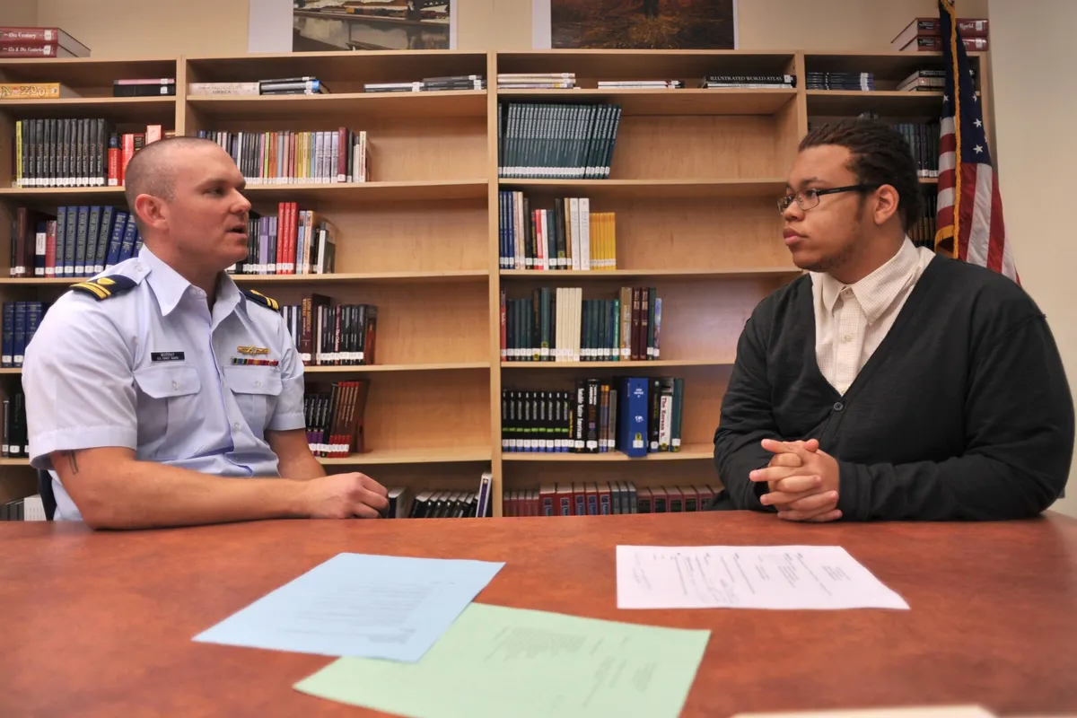A retired officer runs a mock scholarship interview with a high school student across a table