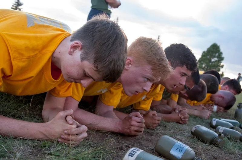 NROTC midshipman candidates holding a timed plank in a line during physical training