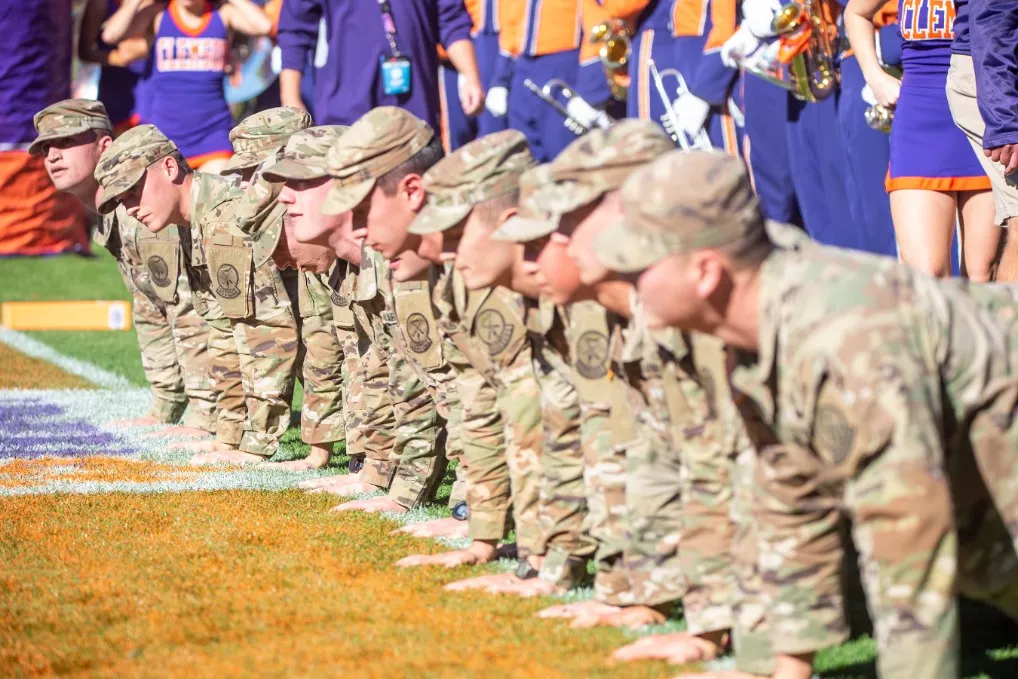 Army ROTC cadets in uniform walking across a college campus between classes